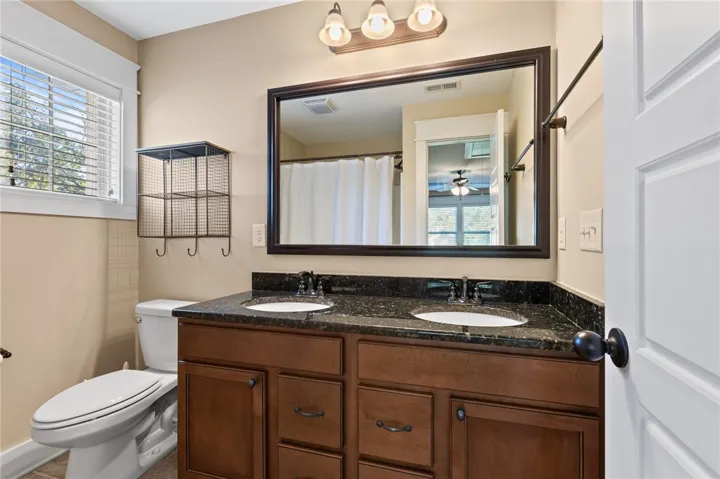 Polished stone counters elevate this functional bathroom space featuring a dual sink vanity.