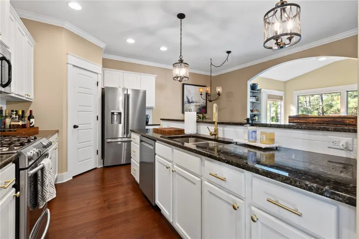 Rich hardwood flooring complements dark stone countertops and crisp white cabinetry in this functional space.