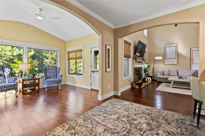 Arched transitions link open living spaces showcasing rich hardwood floors and classic crown moldings.