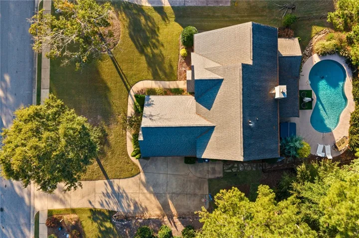 An aerial perspective showcases a sprawling yard with a custom pool and mature trees.