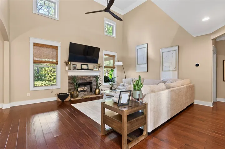 Soaring vaulted ceilings and a stone fireplace anchor this warm living space with hardwood floors.