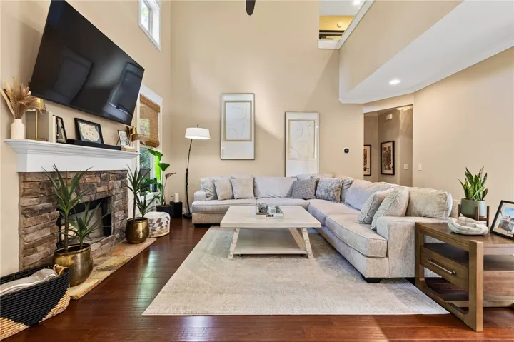Warm hardwood floors complement the rustic stone fireplace beneath towering high ceilings.