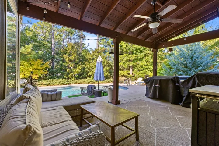 An inviting covered patio features a rustic wood ceiling and overlooks a sparkling swimming pool.