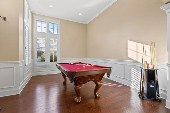 Rich hardwood flooring complements classic wainscoting and tall windows topped with elegant crown molding.
