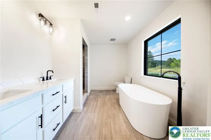 Large primary bath with soaking tub, double vanity and beautifully tiled shower.
