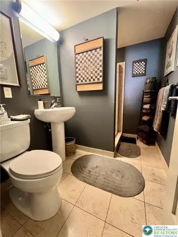 Second bath features a beautiful tiled shower. The artisan-crafted iron towel holder is an exception to sale (goes with the Seller).