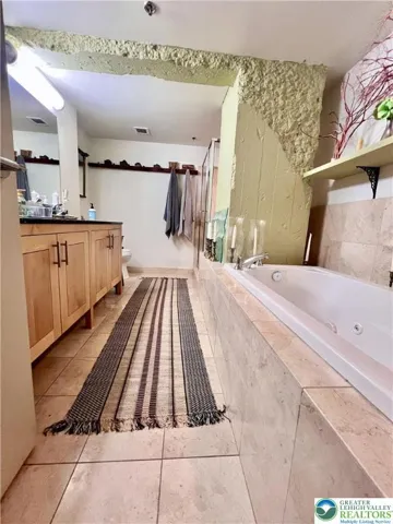 Spacious bath for primary bedroom includes a beautiful tiled shower and jetted tub