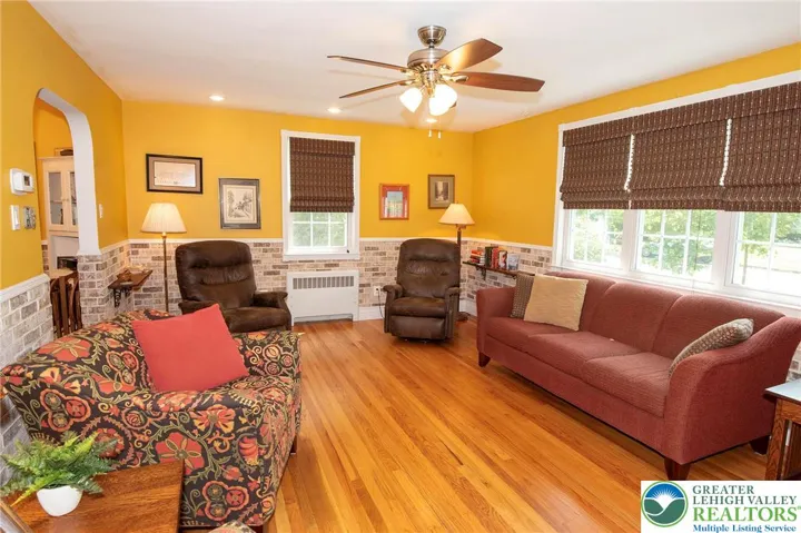 Spacious living room w/newer window blinds, custom thin brick wainscoat, ceiling fan & pot lights.