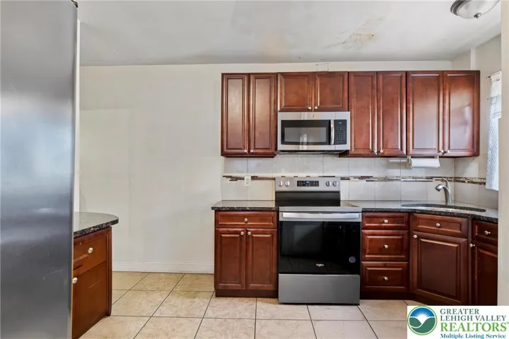 Kitchen- granite countertops, stainless steel appliances, tile floor and tile backsplash