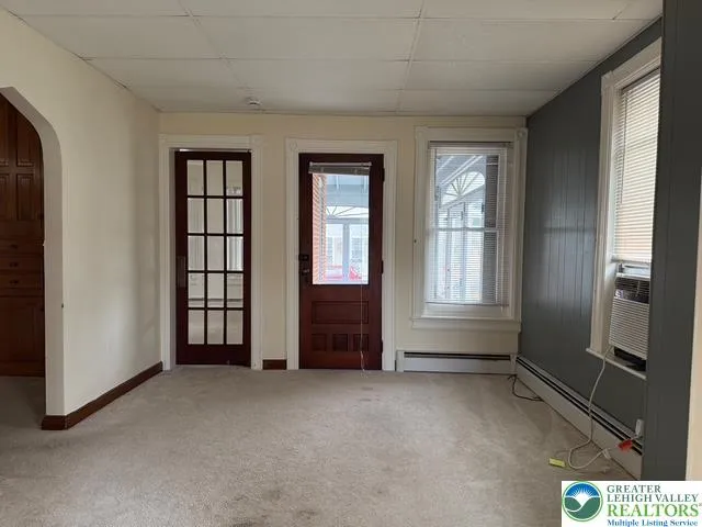living room with access to shared front sunroom, bedroom and den