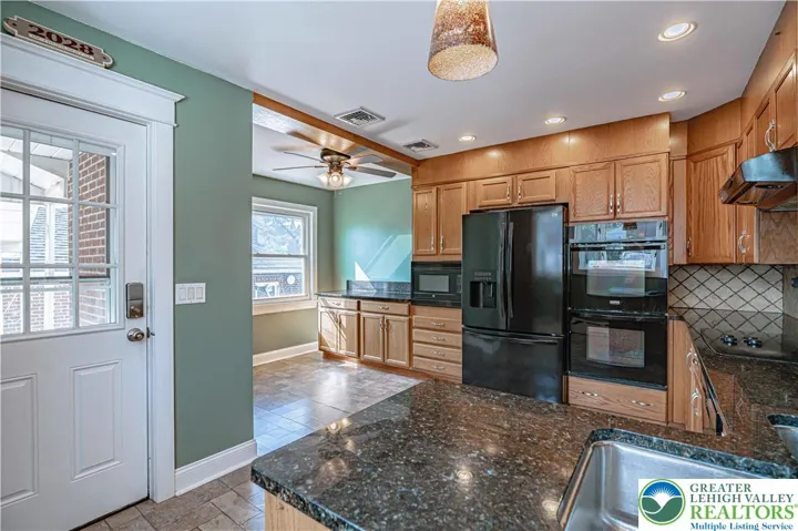 Massive kitchen leading to the fenced-in backyard with a large patio, covered patio, and an oversized garage.