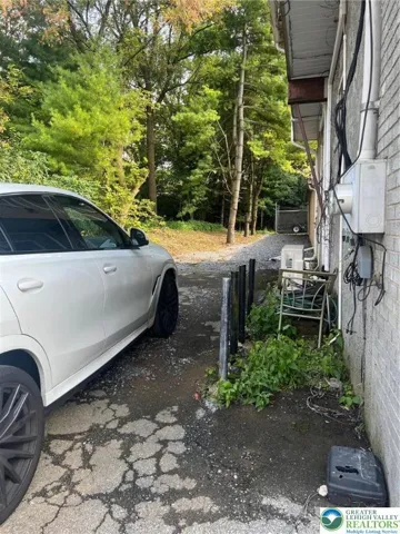 Trash cans are housed for apartment agains the wall between driveway and building