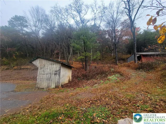 Narrow road to upper part of lot starts behind small shed to right of home