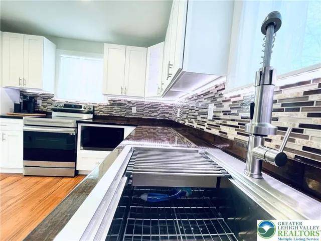 Modern kitchen fixtures, tile backsplash, stainless steel appliances.