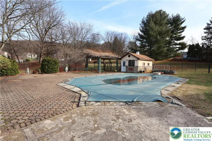 Pool with 55x21 ft patio surround, pergola, and pool house