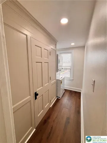 laundry area with stackable washer dryer and storage closet