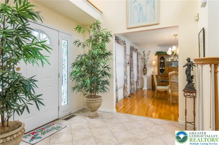 A large, neutral tile foyer is flanked by formal DR & LR. The Palladian window above the door has an outlet for holiday decor.