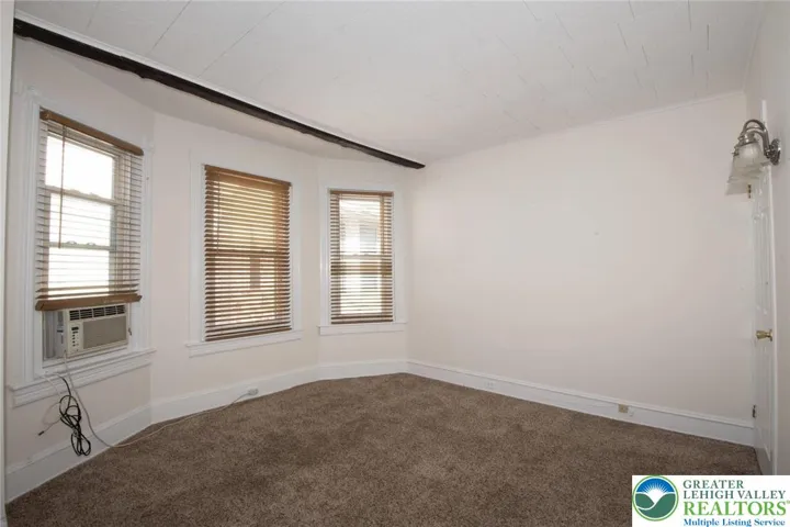 large room features wooden custom window treatments, window A/C, and w/w carpeting