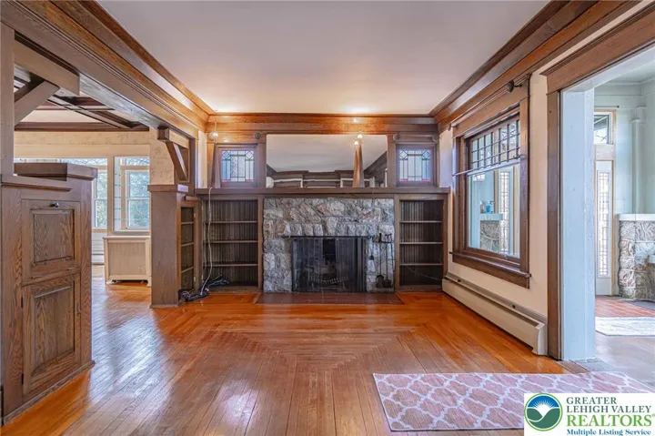 Living room with stone fireplace, built in bookcases and stained glass windows
