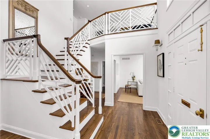 Chinese Chippendale stairway in the two-story foyer, featuring geometric fretwork, lattice motifs, and refined, historic-inspired millwork that adds ornamental elegance and visual interest to the entry space.