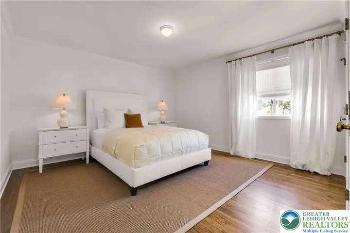 arge bedroom with hardwood flooring and closets featuring built-in storage—spacious, organized, and bright.