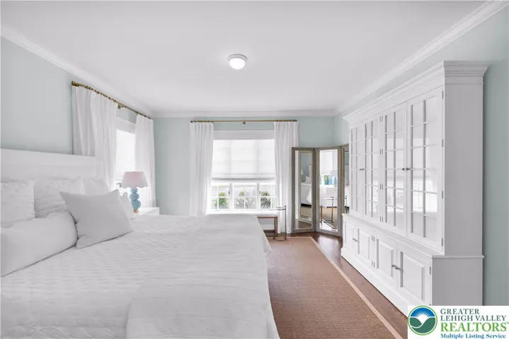 First-floor luxury primary suite with rich hardwood flooring, dual custom closets with built-in storage