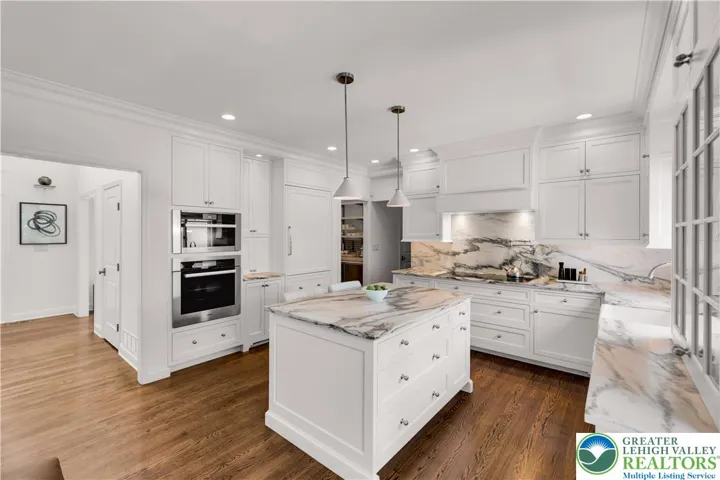 Custom Jill Jarrett kitchen featuring marble countertops and a large center island, bespoke cabinetry, integrated Sub-Zero refrigeration, premium Miele appliances including steam oven and warming drawer, and thoughtfully designed storage and task lighting—an elegant, chef-ready culinary space.