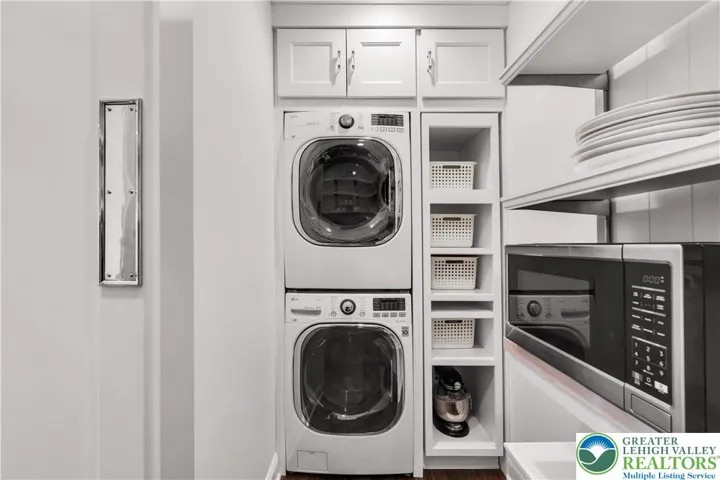 
Stackable washer and dryer tucked into a dedicated laundry area with custom shelving and cabinetry—efficient, space-saving design with organized storage for supplies.