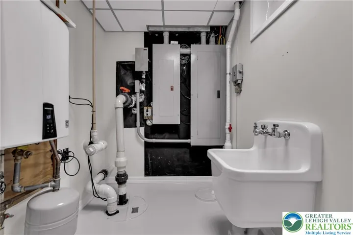 
Utility room housing multiple electric panels (including 400A and 200A service), instant hot-water heater, utility sink, grinder pump, and sump pump — all consolidated in one dedicated, service-ready space for easy access and maintenance.