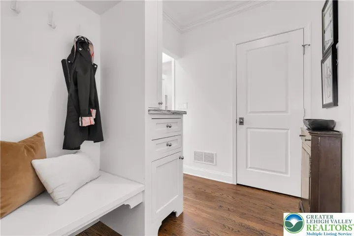
Entry bench with custom cabinetry for optimum storage, hardwood floors, and a coat closet fitted with bespoke millwork—stylish, highly functional organization for everyday convenience.