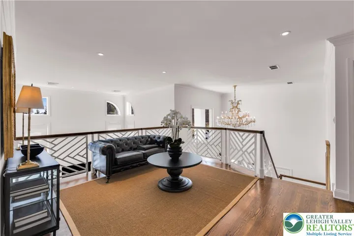 Loft at the top of the staircase with hardwood floors, abundant natural light, and versatile space for seating, a study nook, or play area.
