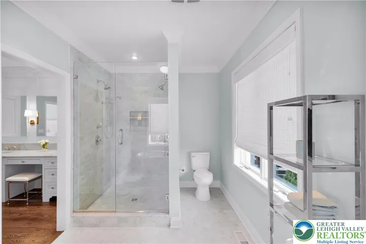 
Spa-style bath with Carrara marble flooring, dual shower heads, and a deep soaking tub—an elegant, private retreat with premium finishes