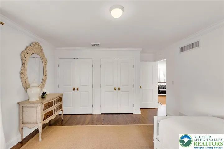 
Large bedroom with hardwood flooring and closets featuring built-in storage—spacious, organized, and bright.