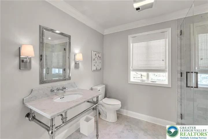 Main bath with Carrara marble floors, a rainhead in shower, and an extended linen closet with ample built-in storage—spa-like, spacious, and highly functional.
