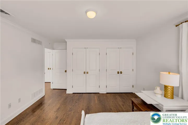 
Large bedroom with hardwood flooring and closets featuring built-in storage—spacious, organized, and bright.