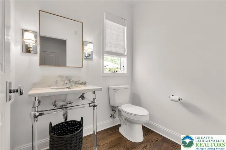 Bathroom featuring a Restoration Hardware lucite pedestal sink, hardwood flooring, polished fixtures, and minimalist finishes for a modern, airy aesthetic.