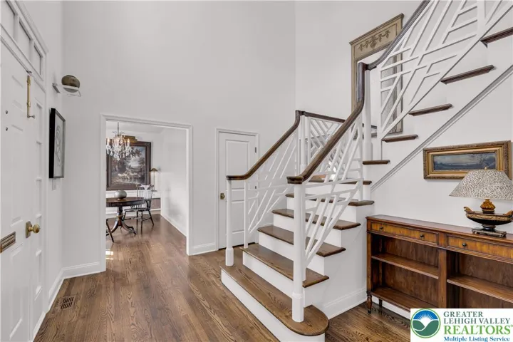 Chinese Chippendale stairway in the two-story foyer, featuring geometric fretwork, lattice motifs, and refined, historic-inspired millwork that adds ornamental elegance and visual interest to the entry space.