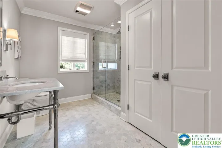 Main bath with Carrara marble floors, a rainhead in shower, and an extended linen closet with ample built-in storage—spa-like, spacious, and highly functional.