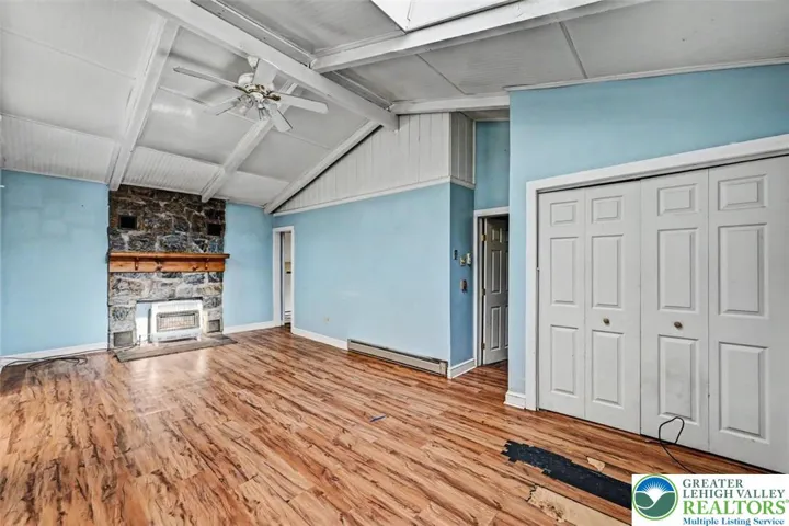 The Living Room as a vented propane heater in front of the Fireplace with floor-to-ceiling stone surround and a wood mantle.
