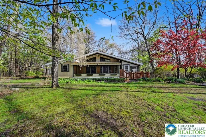 The home has T-1-11 siding and a large screened front porch.
