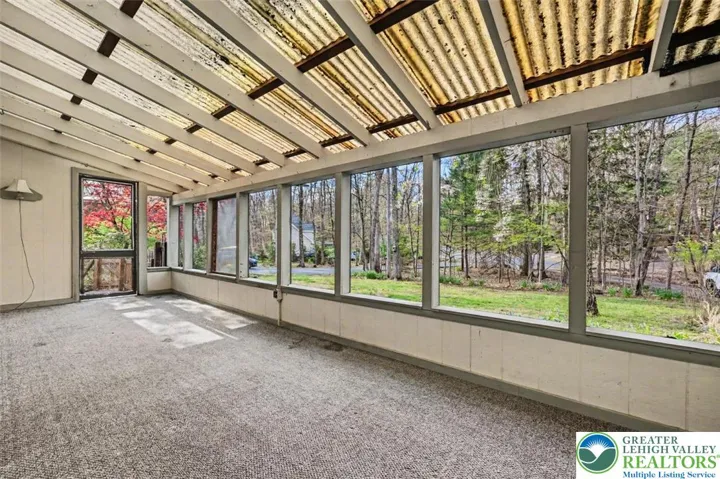 The screened porch is spacious with a wall of windows overlooking the front lawn.
