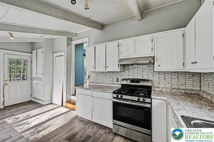 The Kitchen has ample painted cabinetry and includes a newer laminate countertop and tiled backsplash.
