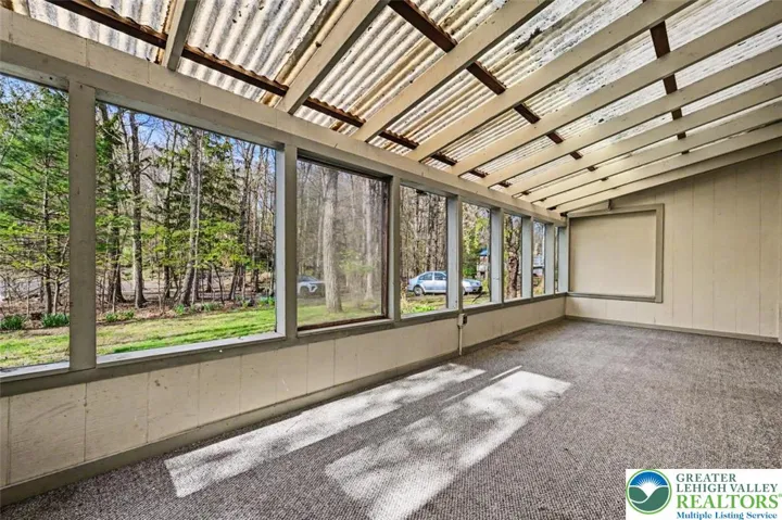 The screened porch has a vaulted corrugated ceiling and outdoor carpeting.
