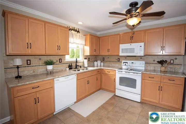 plenty of space for any chef in the modern kitchen with quartz countertops, crown molding, and tiled backsplash