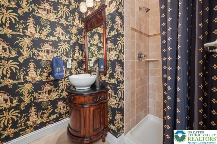 Intriguing 1st floor full bath is adjacent to the home office.  The ceiling-to-floor designer shower curtain when fully closed hides the shower.  Attention to detail!