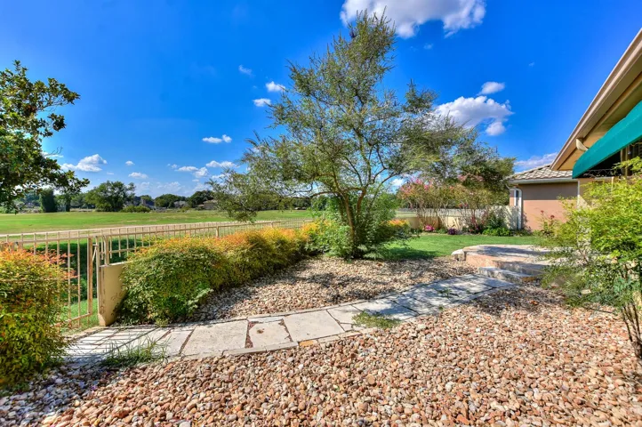 A stone sidewalk leads to the gate which opens up to the golf course...