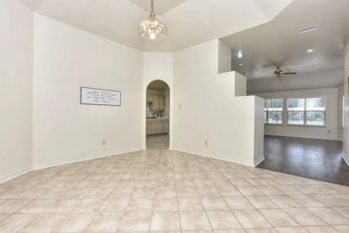 Formal dining room area with tall ceiling and tile flooring laid on an angle... Archway leads to the kitchen...