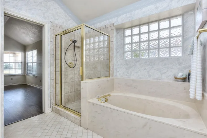 Primary bath has a separate shower and a garden tub.  Small tile floors with tile laid on the diagonal...