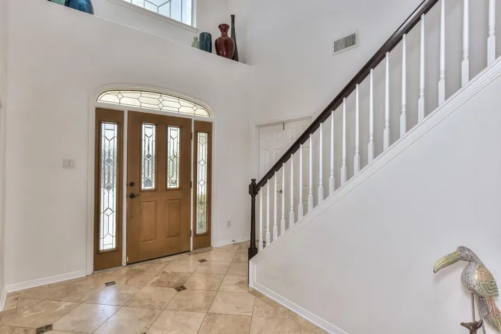 Enter the glass paned front door to a foyer with a soaring ceiling, a window for natural light, and a ledge for your decor...