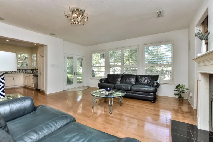 Another view of the family room showing the wall of windows with Plantation shutters and a rear glass-paned door leading to the back yard.